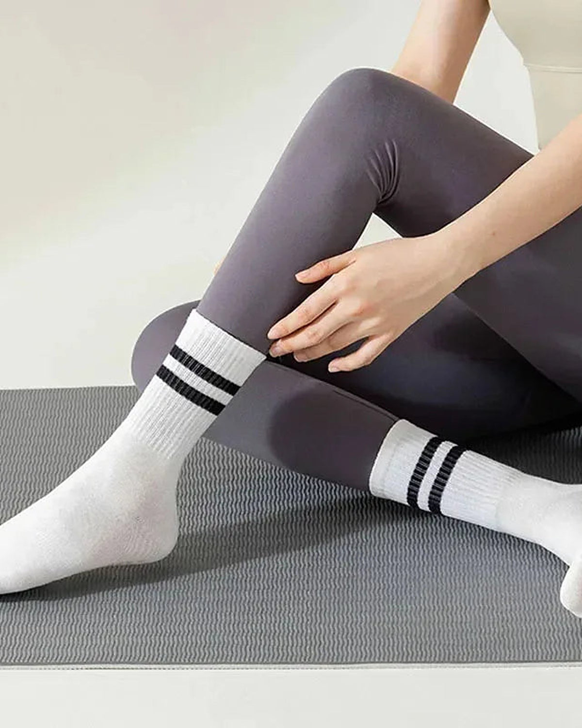 White striped grip socks worn on a pilates mat